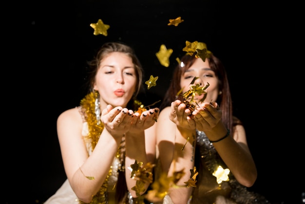 Jeunes femmes avec des guirlandes soufflant sur des étoiles en papier ornement