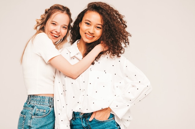 Jeunes femmes insouciantes posant sur un mur gris en studio