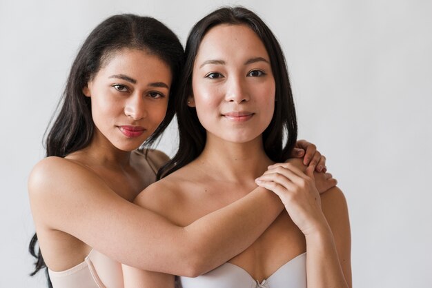 Jeunes femmes multiethniques dans les soutiens-gorge embrassant