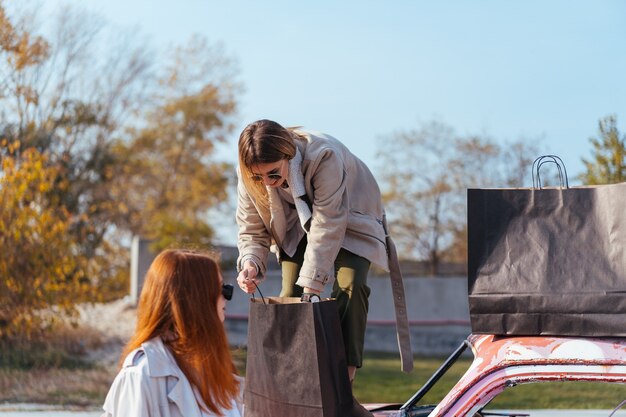 Jeunes femmes posant près d'une vieille voiture décorée