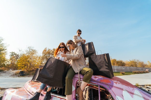 Jeunes femmes posant sur la vieille voiture décorée