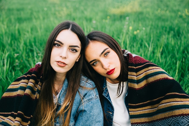 Photo gratuite jeunes femmes regardant la caméra grave avec couverture