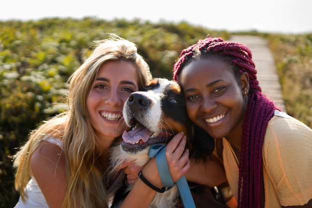 Jeunes femmes s'amusant avec un chien à la plage