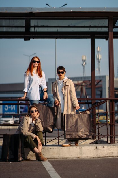 Jeunes femmes avec des sacs à provisions sur un arrêt de bus