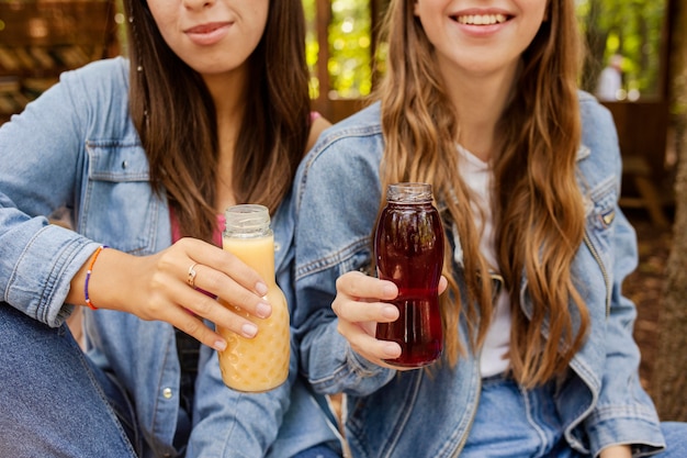 Jeunes femmes tenant des bouteilles de jus de fruits frais