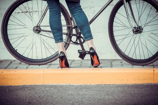 Les jeunes femmes et un vélo en face de la ville