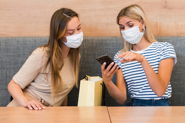 Jeunes femmes vérifiant le téléphone mobile ensemble