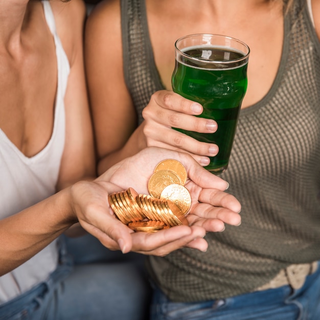 Jeunes femmes avec verre de boisson et tas de pièces