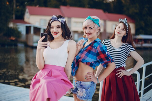 Les jeunes filles posant sur une balustrade blanche et un en regardant son téléphone portable