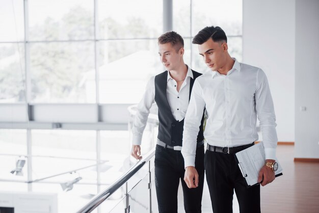 Les jeunes gens d'affaires à la recherche de documents et de produits debout à la balustrade du bureau