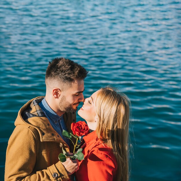 Jeunes gens amoureux avec rose sur le front de mer