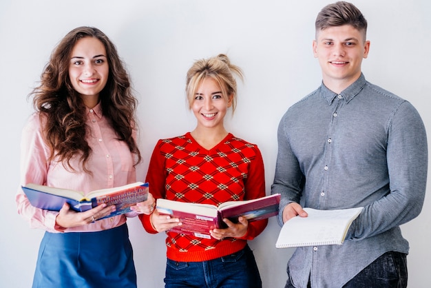 Jeunes gens debout tenant des livres ouverts en studio