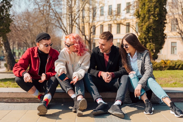 Jeunes gens discutant assis sur un trottoir