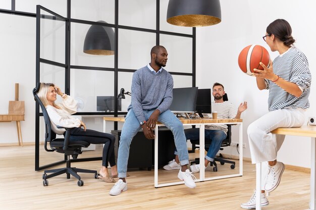 Jeunes gens jouant avec ballon au bureau