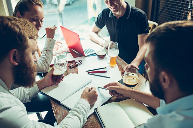 Les jeunes gens joyeux sourient et font des gestes tout en se relaxant dans un pub.