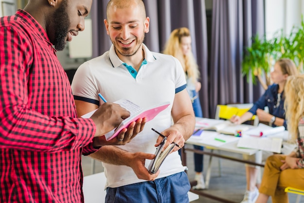 Des jeunes hommes collaborent sur le bloc-notes avec des matériaux