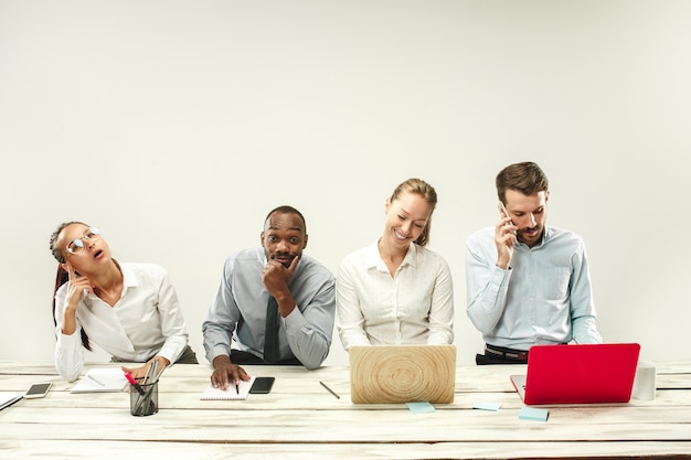 Photo gratuite jeunes hommes et femmes assis au bureau et travaillant sur des ordinateurs portables.