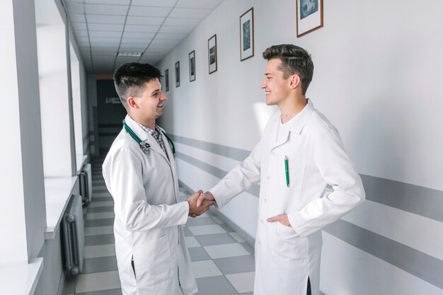 Jeunes médecins se serrant la main dans le couloir