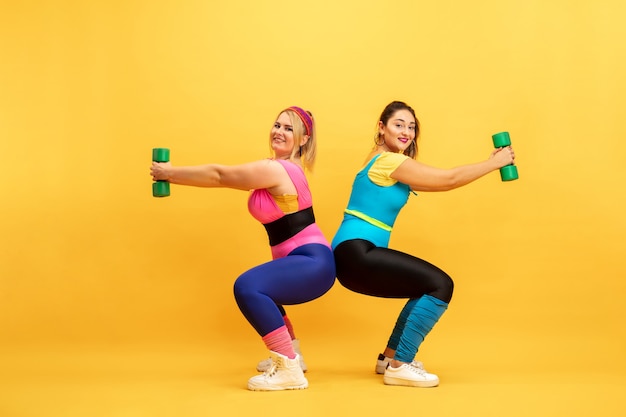 Les jeunes modèles féminins de taille plus caucasien formation sur mur jaune