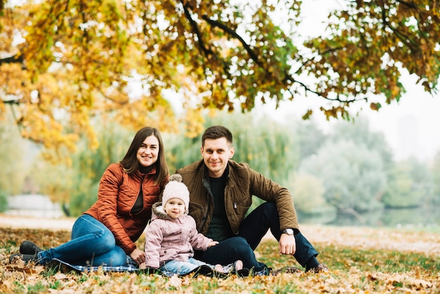 Jeunes parents avec petite fille se reposant dans la forêt d&#39;automne