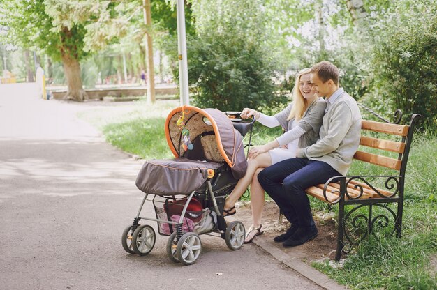 Les jeunes parents de rire avec la poussette dans le parc