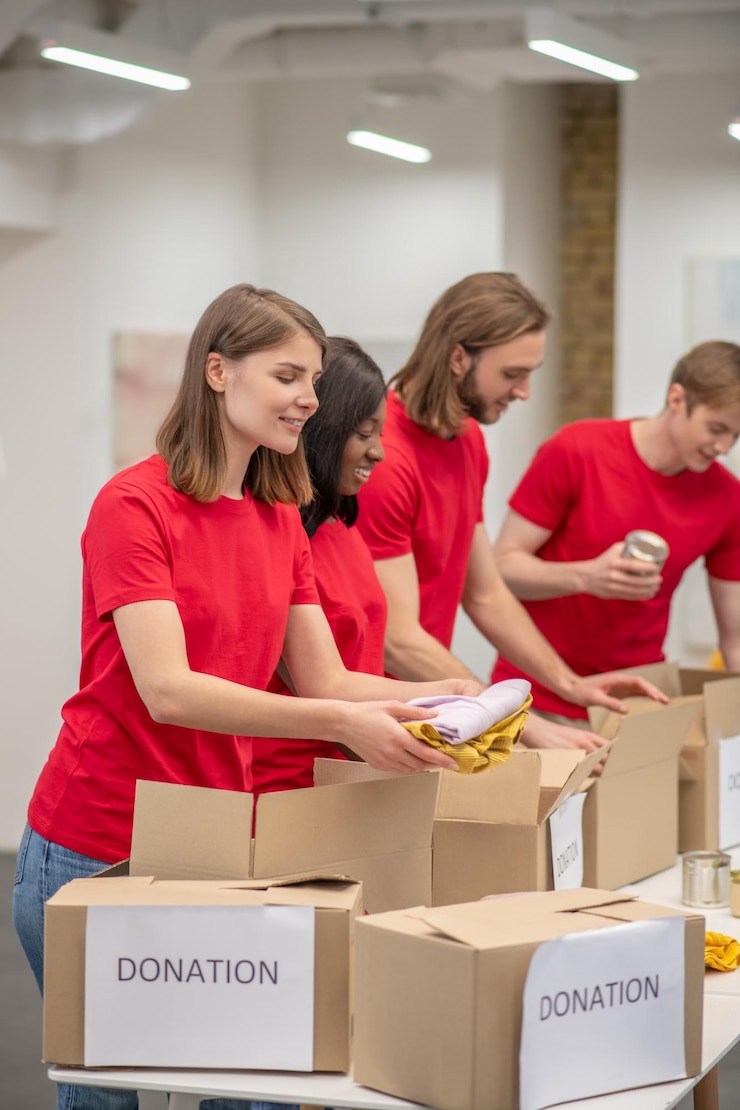 Photo gratuit jeunes personnes en rouge emballant les cartons avec de l'aide humanitaire