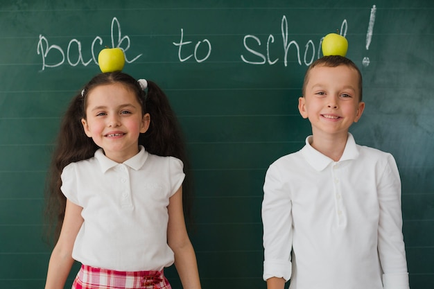 Photo gratuite les jeunes posent avec des pommes dans la salle de classe