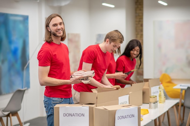 Jeunes en rouge emballant les cartons avec l'aide humanitaire