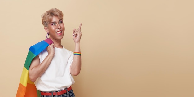 Jeunes transgenres asiatiques LGBT debout avec le doigt pointé isolé sur fond de couleur nude