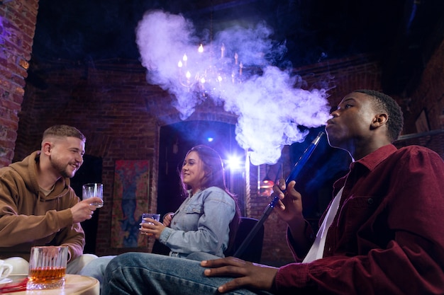 Les jeunes vapotant d'un narguilé dans un bar