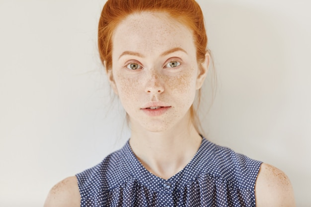 Photo gratuite jeunesse et tendresse. close up portrait of teenage girl aux cheveux roux et une peau saine avec des taches de rousseur portant une chemise sans manches avec des taches