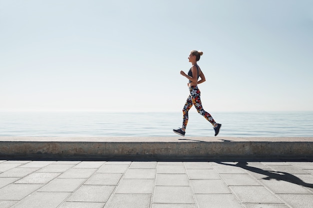 Jogging jeune femme qui court sur le rivage