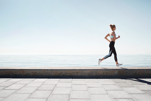 Jogging jeune femme qui court sur le rivage