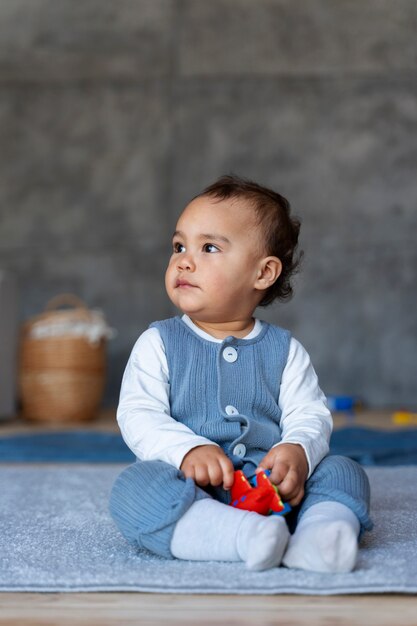 Joli bébé jouant avec un jouet assis sur le sol