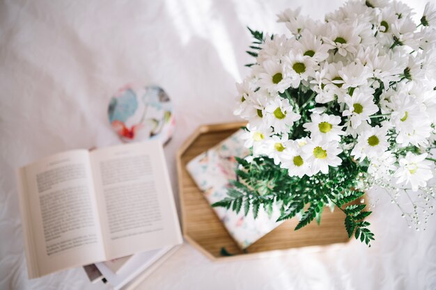 Joli bouquet sur plateau près de livre ouvert