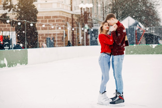 Joli couple dans un chandails rouges s'amuser dans une patinoire