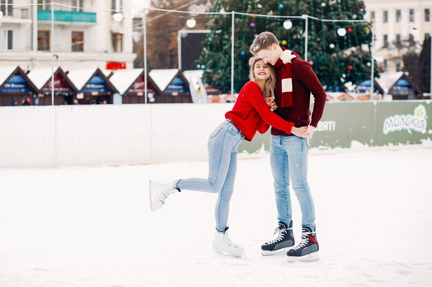 Joli couple dans un chandails rouges s'amuser dans une patinoire