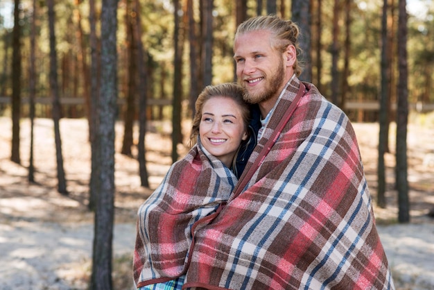 Photo gratuite joli couple enveloppé dans une vue de côté de couverture