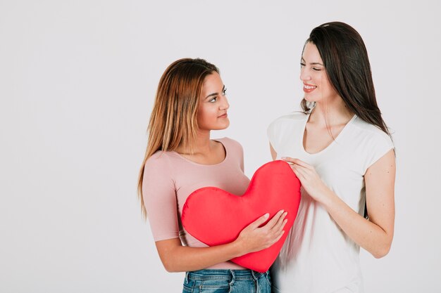 Joli couple de femmes posant avec coeur