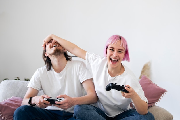 Photo gratuite joli couple jouant à des jeux vidéo sur le canapé