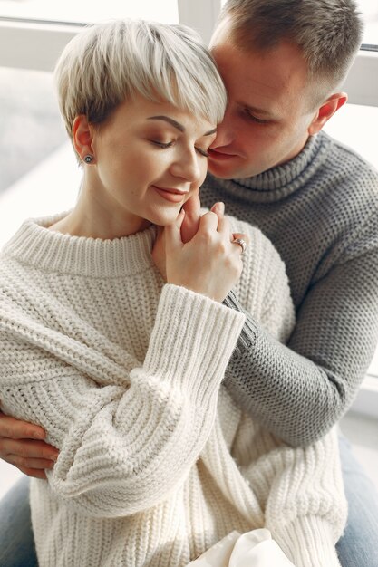 Joli couple à la maison. Dame dans un pull blanc.