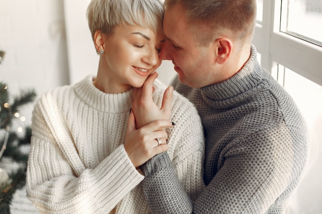 Joli couple à la maison. Dame dans un pull blanc.