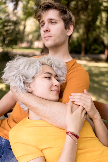 Joli couple se détendre ensemble sur un banc alors que dans le parc