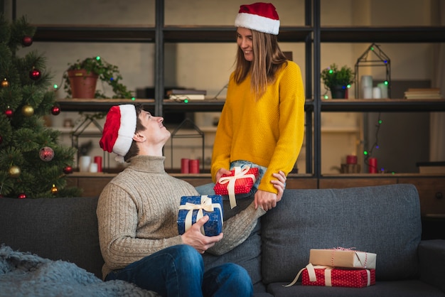 Joli couple tenant des cadeaux dans le salon