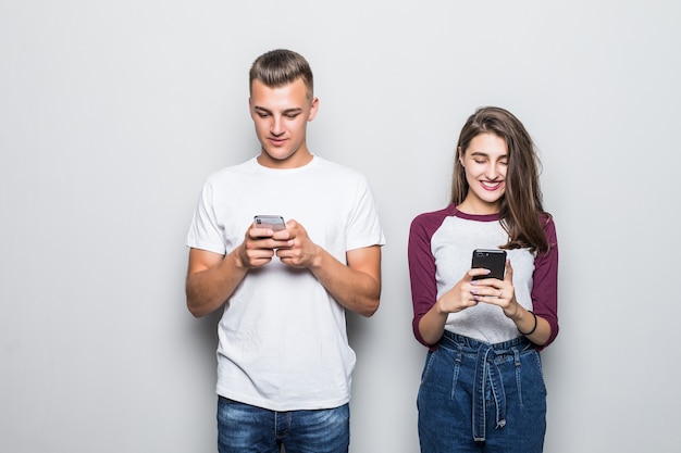 Joli jeune beau couple garçon et fille avec leurs téléphones isolés sur blanc