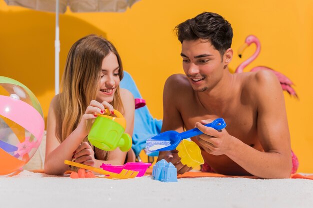 Joli jeune couple jouant des jouets pour bac à sable en studio