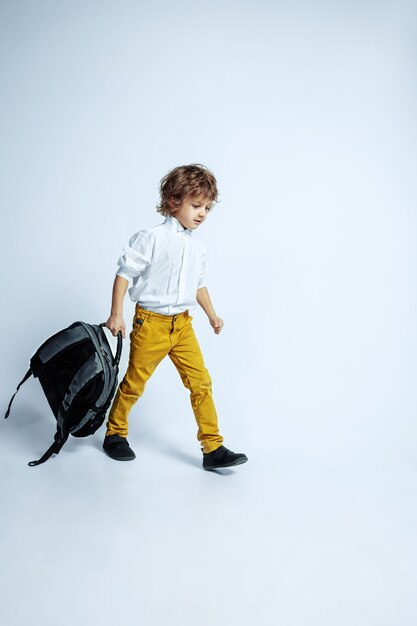 Joli jeune garçon en vêtements décontractés sur blanc. Pose à la mode