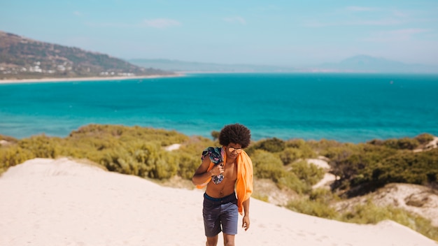 Photo gratuite joli jeune homme marchant au bord de la mer