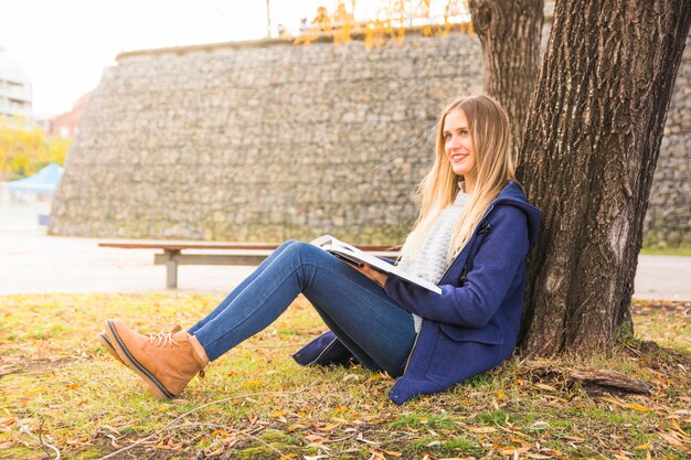 Joli modèle assis arbre incliné et lecture