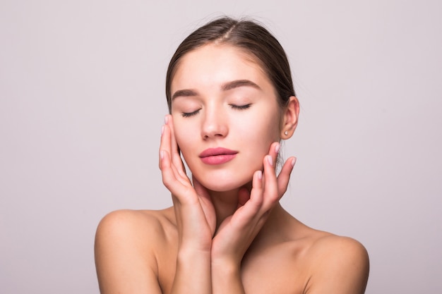 Joli visage de belle femme souriante posant au studio isolé sur mur blanc